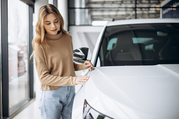 Woman choosing a car in car showroom