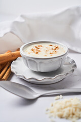 Delicious rice pudding or arroz con leche with cinnamon in bowl on a white marble background