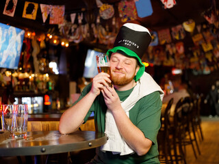 ginger man in leprechaun hat hugging glass of beer