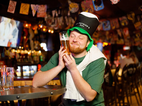 ginger man in leprechaun hat for st patricks day hugging glass of beer