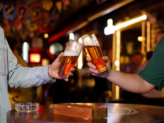 Two men drinking beer at the bar. They celebrate St. Patrick's Day. They are having fun
