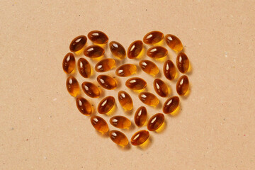 Omega 3 Fish Oil capsules in heart shape on recycled paper background - Concept of vitamins, supplements and heart health