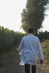 Attractive young farmer smiling standing in corn field.  shallow depth of field, follow focus, blur.