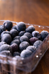 frozen blueberries in a bowl on wooden background