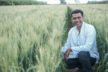 Happy young farmer siting and smiling in his field.shallow depth of field, follow focus, blur.
