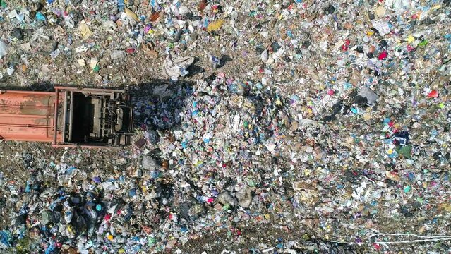 Aerial top down view of truck unloading garbage, waste at landfill. Trash truck dump waste products polluting in an trash dump.