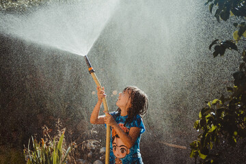 Girl playing with a watering hose in summer.
