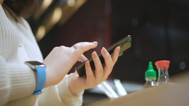 Close view of the female hands using smartphone, texting. Young lady standing at shopping mall. Woman after shopping using smartphone for online shopping