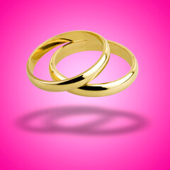 old wedding rings floating against pink background