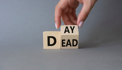 Day of the Dead symbol. Businessman hand turns wooden cubes and changes word Dead to Day. Beautiful grey background. Day of the Dead concept. Copy space.