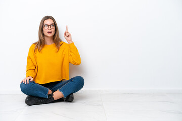 Young caucasian woman sitting on the floor isolated on white background intending to realizes the solution while lifting a finger up - Powered by Adobe
