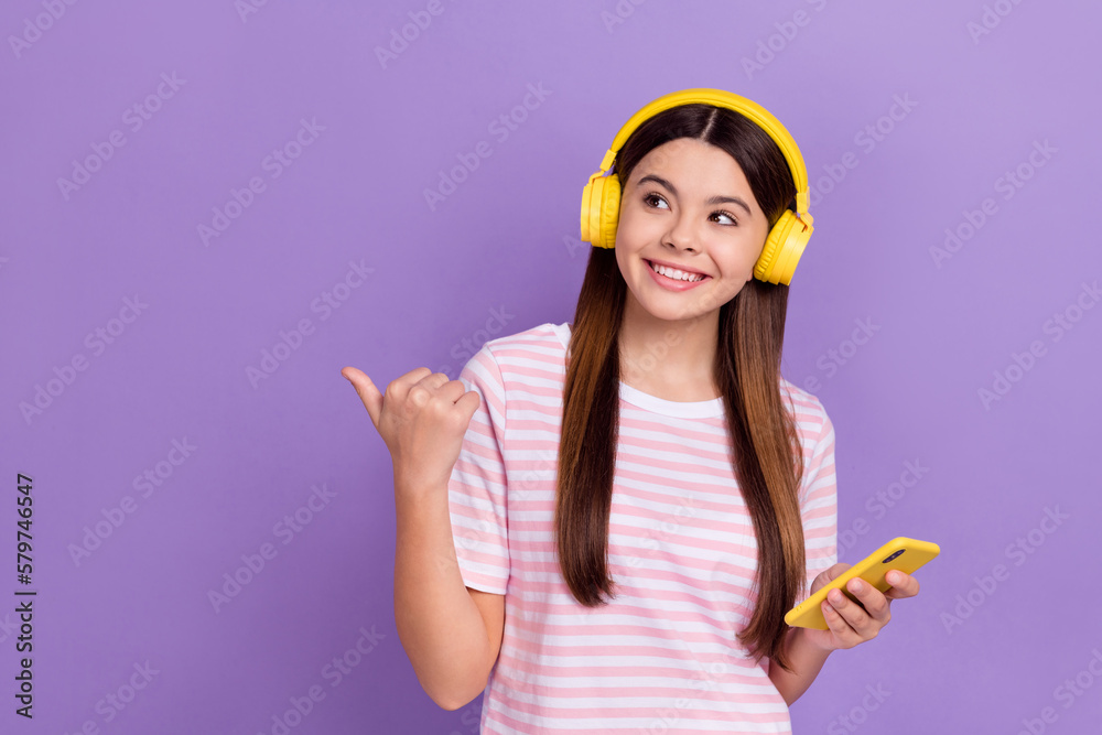 Wall mural Photo of shiny dreamy girl dressed striped t-shirt enjoying songs modern gadget thumb empty space isolated purple color background