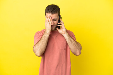 Handsome blonde man using mobile phone over isolated background with tired and sick expression