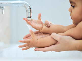 Raising a happy and healthy baby. Shot of a woman washing her babys hands under running water.