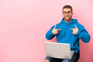 Young man sitting on a chair with laptop with surprise facial expression