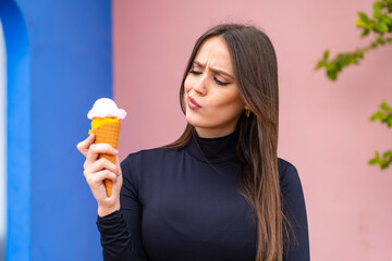 Young pretty woman with a cornet ice cream at outdoors with sad expression