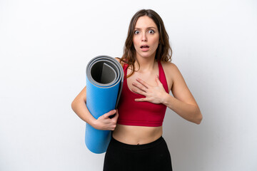 Young sport caucasian woman going to yoga classes while holding a mat isolated on white background surprised and shocked while looking right