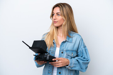 Young Uruguayan woman holding a drone remote control isolated on white background looking to the...