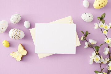 Easter concept. Flat lay photo of envelope with white card colorful easter eggs butterfly shaped cookies and spring blossom branch on isolated violet background