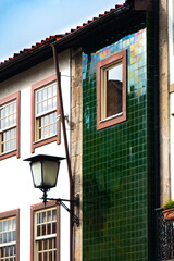 Details of the lamp reflected in furtacor green ceramics on the facade of a building in Braga, Portugal