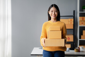 A beautiful business owner opens an online store, she is checking orders from customers, sending goods through a courier company, concept of a woman opening an online business.