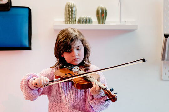 Cute child practicing violin in bedroom