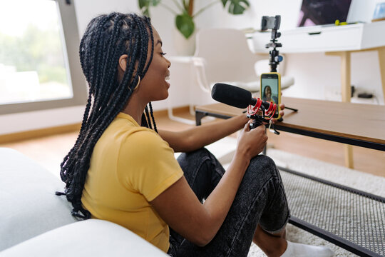 Cheerful black woman recording voice podcast with microphone