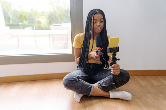 Black woman recording voice podcast with microphone