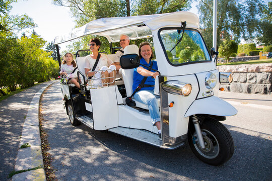 A group of tourists driving through the city center in tuk-tuk electric car. Travelers enjoying a ride on environmentally friendly transport in the old town
