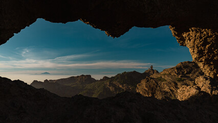 View of Roque Nublo Volcanic Crag Through Arch Rock Formation in Gran Canaria, Spain - obrazy, fototapety, plakaty