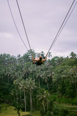 Rear view woman on a swing at vacation in Bali, Indonesia. Young girl traveler sitting on the swing...