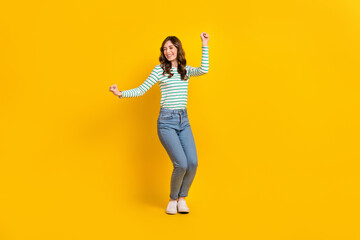 Fototapeta na wymiar Full size photo of pleasant gorgeous woman curly hairstyle striped shirt clenching fists dancing isolated on yellow color background