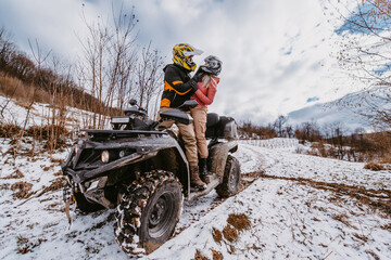 Couple enjoying while driving quad bike on top of mountain at winter time © Minet