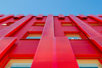 Modern red architectural office building. Metal sheets covering the exterior of the structure....