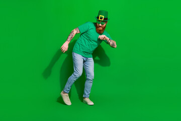 Full length photo of positive funky guy dressed t-shirt shamrock eyewear having fun isolated green color background