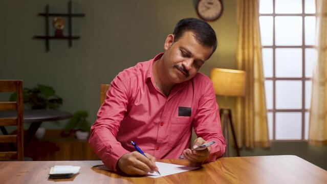 Middle aged family man doing monthly budget calculation after salary at home - concept of middle class lifestyle, savings and expenses planning.