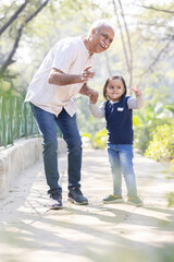 Carefree grandfather having fun with granddaughter at park