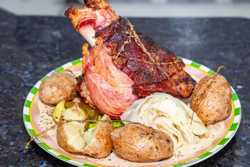 Roasted smoked pork knuckle with typical side dishes, traditional German dish, isolated portrait in selective focus.