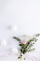 Easter composition made with flowers, eucalyptus branches and eggs on white background  copy space. Creative minimal holiday concept.
