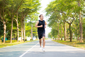 happy young Asian handsome man enjoys his running  in city public park during a summer day, sporty...