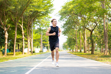 Fototapeta premium happy young Asian handsome man enjoys his running in city public park during a summer day, sporty guy spend quality time on weekend jogging outdoor in nature for healthy and active lifestyle