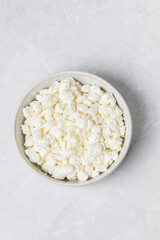 Fototapeta na wymiar Natural cottage cheese in white bowl isolated on light background, top view