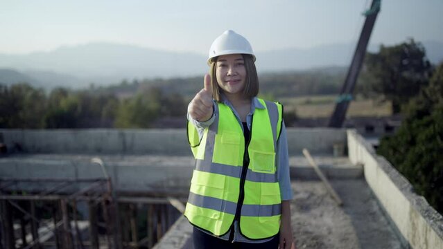 Civil engineer woman thumbs up because the work is going well in Industrial building. Architect on construction site. Construction and architecture. Professional engineer in safety equipment. Reflecti
