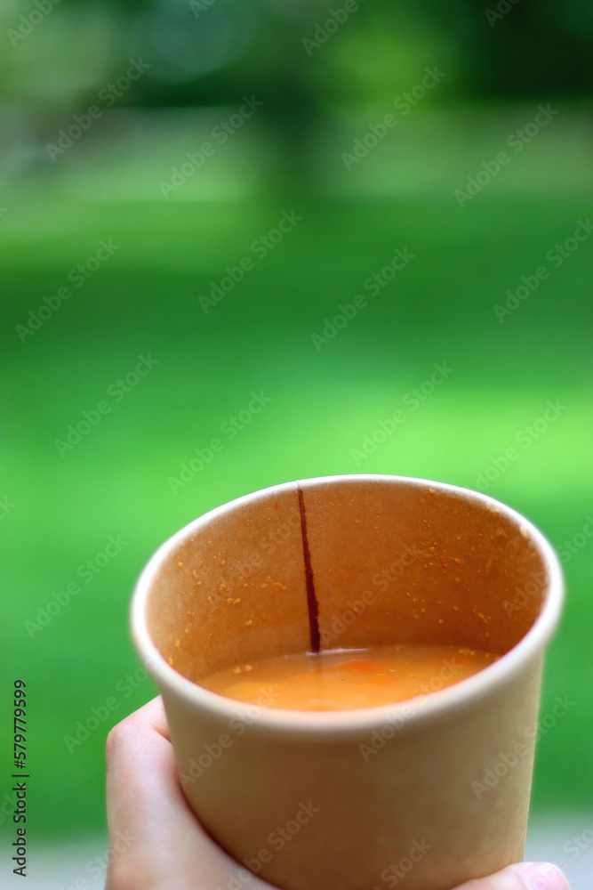 Wall mural paper cup filled with vegetable soup. eating soup outdoor in the park. selective focus.