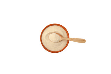 Semolina in clay plate with wooden spoon on white background, top view. Design element, copy space