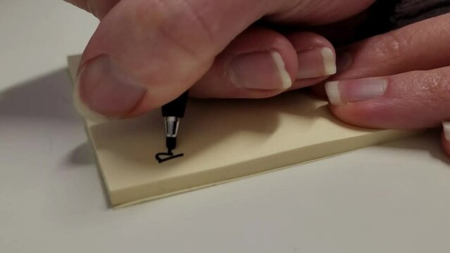 Woman writing on a post it sticky note. Remember to live! Motivational quote.