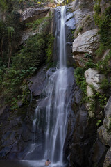 Young woman female bathing in waterfall at Yelapa village, smooth water stream shot with long exposure. Adventure, travel, tourism, hike, explore concept.