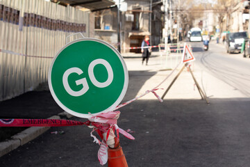 Street photography. Permissive road sign. Green circle with white outline. Go text call. Striped...