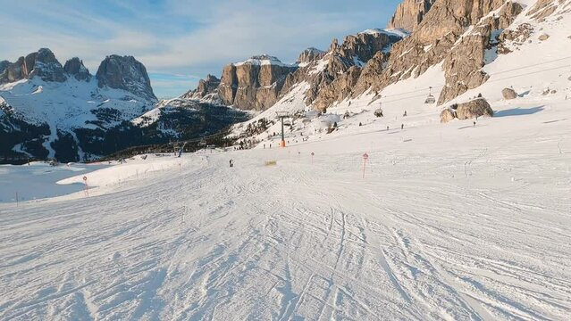 First-person view FPV first-person point of view POV of alpine skiing in Dolomites. Ski resort piste with people skiing in Dolomites in Italy. Ski area Belvedere. Canazei, Italy