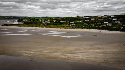 The famous Irish beach of Inchydoney at low tide, top view. Houses on the seashore. Huge sandy beach. Overcast gray sky.